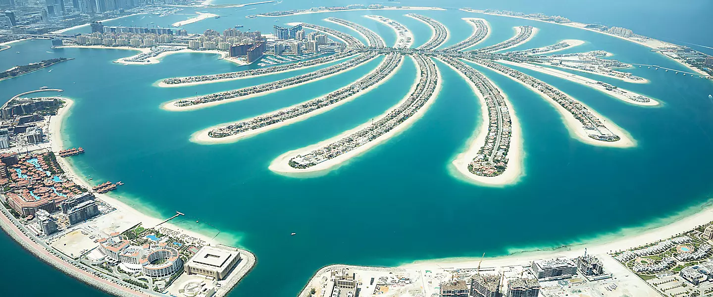 Cruise ship sailing near a modern Middle Eastern skyline and coastline